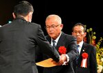 防犯栄誉金章の表彰状を受け取る遠藤さん（中央）＝１８日、鳥取市のとりぎん文化会館
