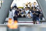 　原爆慰霊碑の前で手を合わせる人たち＝６日午前６時１０分、広島市の平和記念公園