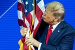 　メリーランド州で開かれた保守政治行動会議（ＣＰＡＣ）の会合で米国旗にキスするトランプ前大統領＝２４日、オクソンヒル（ＡＰ＝共同）