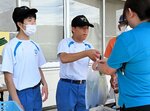 来場者にダイコンを手渡す生徒ら＝１２日、鳥取市伏野の末恒体育館