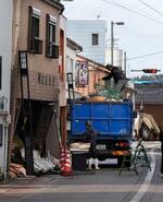 　石川県珠洲市で緊急公費解体が始まり、傾いた住宅から家具などをトラックに積み込む業者ら＝２６日午前