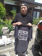　店のシャツを手にする楠さん＝２０２４年５月２６日、石川県輪島市