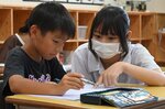 児童（左）に問題の解き方を教える高校生＝２６日、鳥取市立川町５丁目の修立小