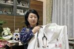 　高島晨伍さんが生前身に着けていた白衣を手にする母親の淳子さん＝２０２４年２月、大阪府