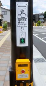 　金沢市内の押しボタン式信号機に貼られた英語表記のステッカー＝７月