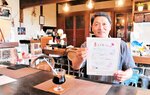 まどぐちカフェのチラシを持つ桑田事務局長。「飲食店をサードプレイスに」と意気込む＝２０日、鳥取市国府町奥谷１丁目の麒麟カフェ