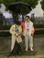 　大会スタッフに傘を差してもらいながら作業する三村舞記者＝９月２２日、杭州（共同＝山内大輝撮影