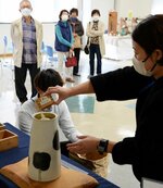 自作の花器にコメを入れて計量する西根さん（右）＝２３日、鳥取市富安２丁目の日本海新聞ビル５階ホール