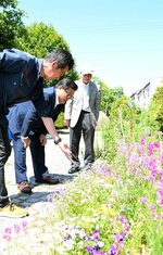 小倉会長（左）から沿道に植えられた草花の説明を受ける広田市長（中央）