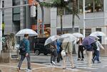 　那覇市内を傘を差して歩く人たち。気象庁は沖縄地方と鹿児島県・奄美地方が梅雨入りしたとみられると発表した＝２１日午前