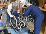 　ＮＰＯ法人「飛んでけ！車いす」の会の事務所で車いすを整備する男性たち＝４月、札幌市