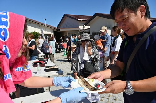 大船渡産のサンマの塩焼きを受け取る来場者＝１６日、鳥取市賀露町西３丁目の地場産プラザわったいな