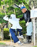 庭木の枝切りをする様子を再現したかかしを作った福山さん。地区内には住民の力作が並ぶ＝７月３１日、朝来市納座地区