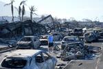 　米ハワイ・マウイ島の山火事で焼けた車の間を歩く男性＝１１日（ＡＰ＝共同）