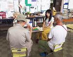 　熊本地震で避難所となった熊本市内の公民館で、高齢男性の話に耳を傾ける松岡優子さん（右から２人目）
