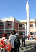 　和歌山県那智勝浦町にあるロケットのモニュメントの前で記念撮影する人たち＝９日午前７時４４分