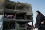 　イスラエル軍の攻撃で破壊された家の前を歩くパレスチナ人の女性＝２２日、ガザ南部ラファ（ロイター＝共同）