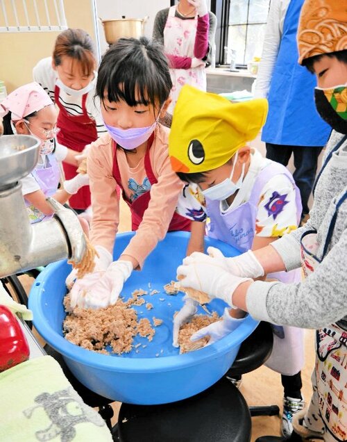 すりつぶした材料を手でこねて丸めていく子どもたち＝２３日、新温泉町丹土の県立但馬牧場公園