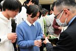 谷本社長（右）に日本酒を注いでもらい、飲み比べをする学生ら＝１９日、鳥取市湖山町南４丁目の鳥取大