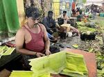 　インド南部チェンナイの青物市場で、バナナの葉を割くセンティル・クマールさん＝２０２４年５月（共同）