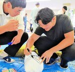 かかしの頭に巻き付けた布にユニークな顔を描く生徒＝２５日、新温泉町芦屋の浜坂高