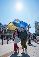 　厳しい暑さの中、東京・浅草の雷門周辺を日傘を差して歩く人たち＝２８日午後