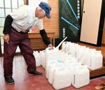 市が用意したポリタンクを手に取る住民。飲料水は給水に頼らざるを得ない生活が続いている＝２４日、倉吉市関金町福原の自治公民館