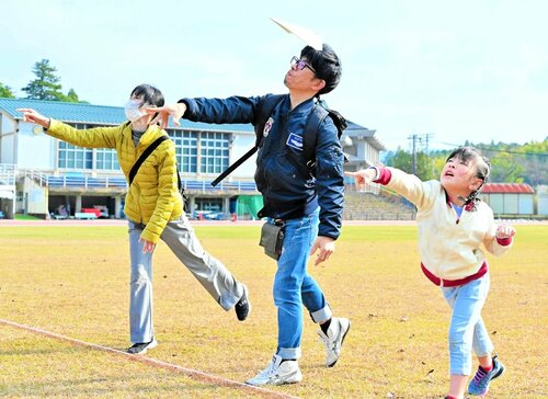 紙飛行機の飛距離を競い合う家族連れ＝２２日、倉吉市営陸上競技場