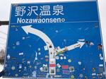 　大量のステッカーが貼られた、野沢温泉スキー場ゲレンデ付近の道路標識＝５日、長野県野沢温泉村（同県提供）