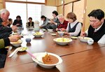 職員手作りのカレーを口に運ぶ住民ら＝２６日、江府町武庫の荒田会館