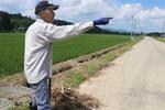 　水没した田んぼの近くで被害の様子を説明する佐々木さん＝７月２３日、秋田県大仙市