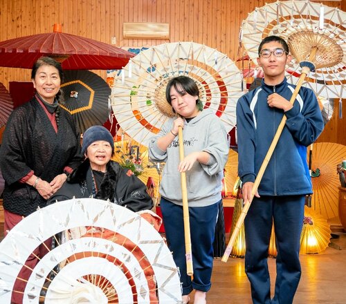 自作の踊り傘を手にする生徒と、指導した山本会長（左から２人目）ら