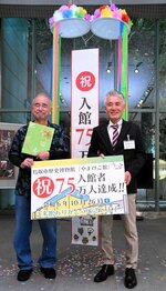 来館者７５万人を記念するパネルを手に持つ西村さん（左）と姫村館長