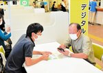 行政サービスに関連するアプリの導入について尋ねる市民（右）＝米子市役所