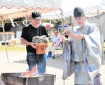 かえる島にちなんだ形の絵馬を焼納する田淵宮司＝２３日、香美町香住区境の今子浦海水浴場