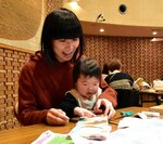 思い出の服で写真立てを作る親子連れ＝２３日、鳥取市西町３丁目のわらべ館