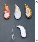 　補聴器（下）の形をモチーフにしたブローチ。左から「さくらんぼレッド」「樹氷ホワイト」「芋煮ブラウン」＝山形市
