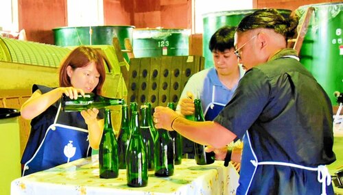 スパークリングワインの最後の仕上げにワインを足す加藤さん（左）と谷さん（右）＝１９日、北栄町松神の北条ワイン醸造所