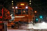 　今季初めて出動し、路面電車の軌道に積もった雪を掃き飛ばす「ササラ電車」＝２４日夜、札幌市