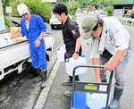 鳥取市職員（中央）が運んできた水を車両に積み込む住民ら＝１８日、同市河内の県道２８１号