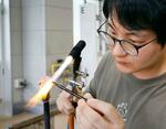 　富山ガラス工房で、ホタルイカをかたどったガラス細工を制作する勝木竜二さん＝２０２４年５月、富山市