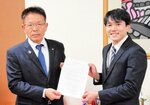 手嶋町長（左）から辞令を手渡され、笑顔を見せる田村さん