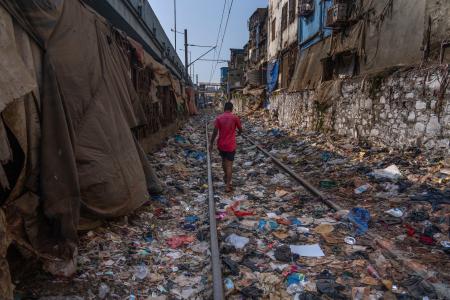 　プラスチックごみなどが散乱した線路を歩く男性＝４月、インド・ムンバイ（ＡＰ＝共同）