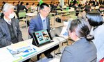 企業の採用担当者から業務内容などの説明を聞く学生（右側２人）＝１４日、豊岡市大手町のアイティ