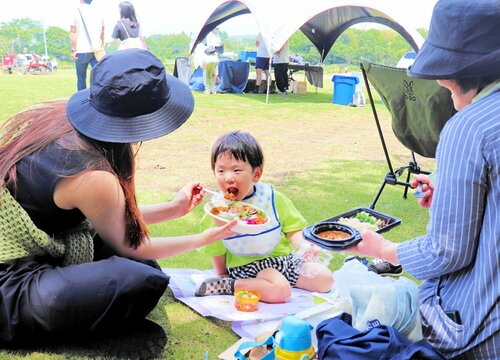 快晴の芝畑で大山野菜カレーを食べる親子ら