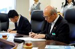 協定書に署名する田村理事長（右）と山本事業責任者＝２２日、鳥取市栄町の鳥取信用金庫
