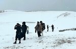 寒風に身をすくめ、雪化粧した砂丘を歩く観光客＝１７日、鳥取市の鳥取砂丘