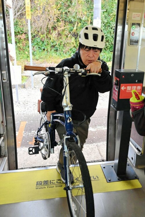 自転車を担いで列車に乗り込むツアー参加者＝９日、大山町御来屋のＪＲ名和駅