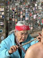 　フィリピン・ルソン島北部ブスカランで、観光客に入れ墨を施すワンオド・オッガイさん＝２０２４年２月（共同）