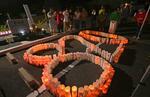 　広島土砂災害から９年となり、慰霊碑前に並べられた灯籠を囲んで黙とうする住民ら＝２０日未明、広島市安佐南区
